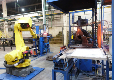 braço mecânico automatizado manipulando aço na fabricação de cilindros para gases